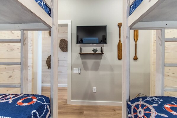 A room with bunk beds, a mounted television, and nautical-themed decor. - Luxury 4-Bedroom Beach Retreat | Private Pool, Boardwalk Access for Golf Carts (Port Aransas)