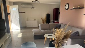 En moderne stue med sofa, sofabord og et spiseområde med bord og stole.