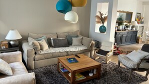 A living room with a sofa, coffee table, and a dining area with a cabinet.