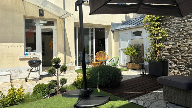 A patio area with a grill, outdoor seating, and a stone wall.