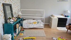 A child's bedroom with a bunk bed, a desk, a dresser, and various toys.