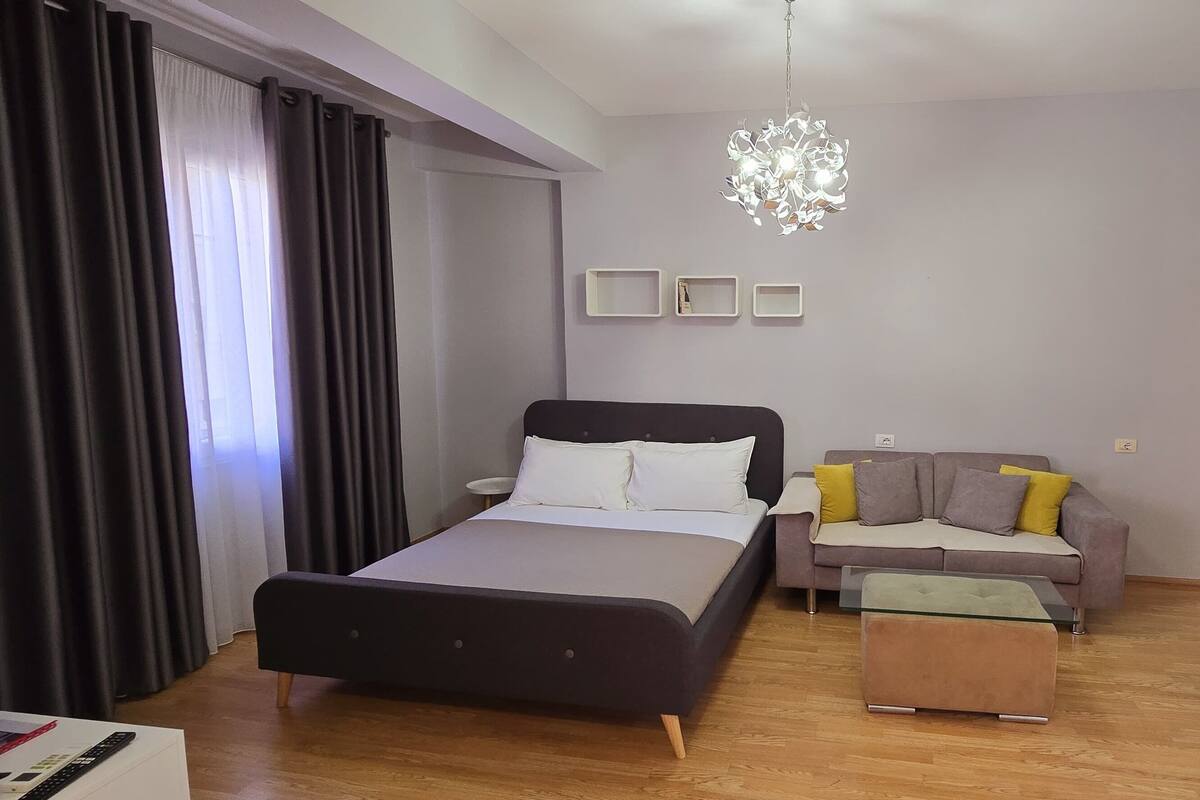 Ein modernes Schlafzimmer mit einem Bett, einer Couch, einem kleinen Tisch und einer Pendelleuchte.