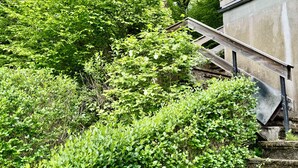 A wooden staircase leading up to a building surrounded by dense green foliage. - Panoramic Chalet (Cenves)