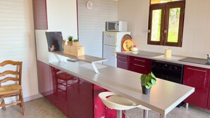 A compact kitchen with a white countertop, red cabinets, a microwave, and a sink. - Panoramic Chalet (Cenves)