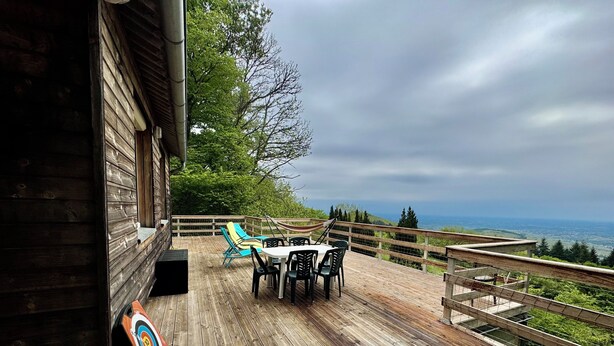 A wooden deck with a table and chairs, a hammock, and a target on the wall. - Panoramic Chalet (Cenves)