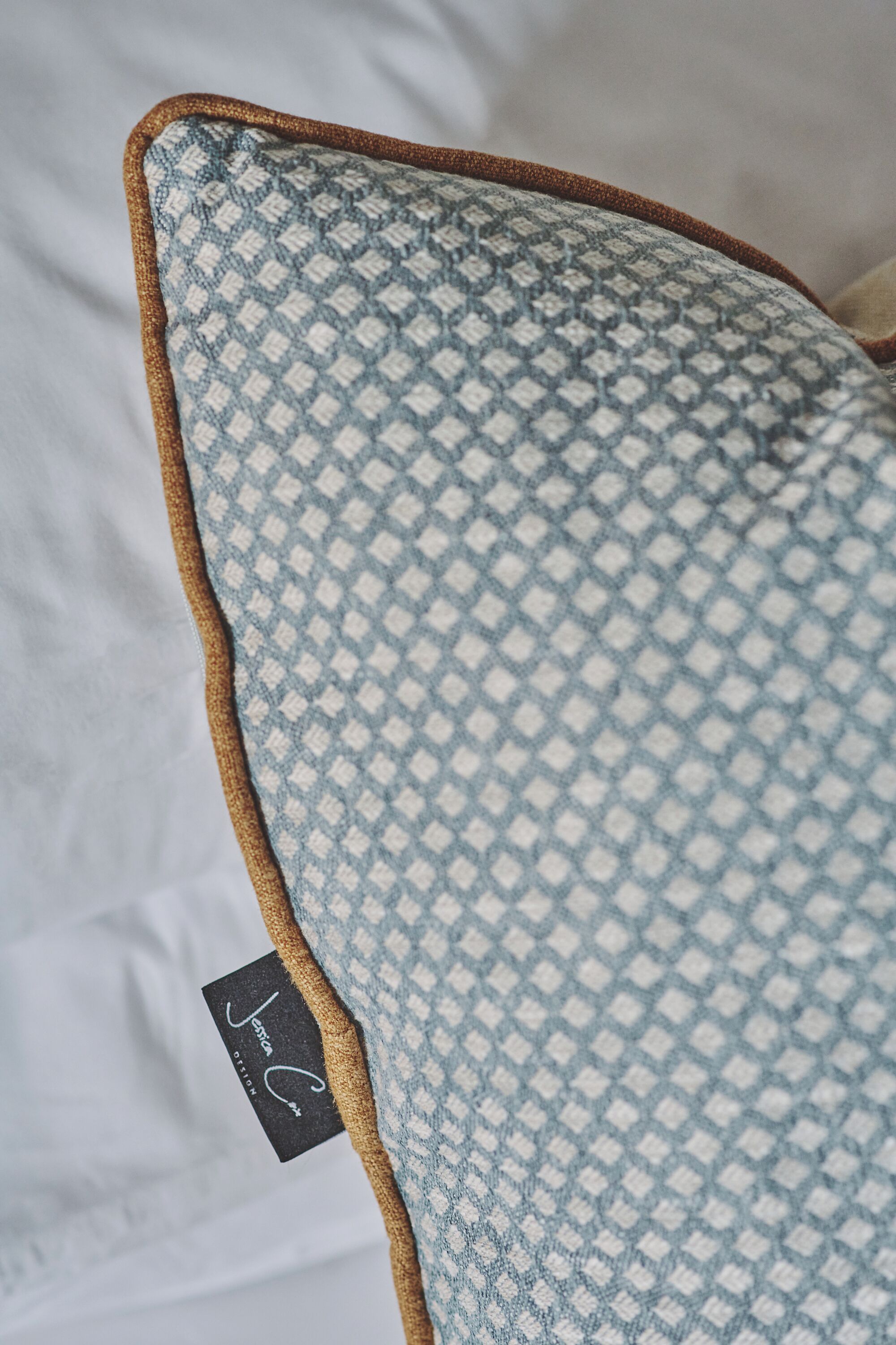 A close-up of a pillow with a checkered pattern and a tag labeled "Jessica."