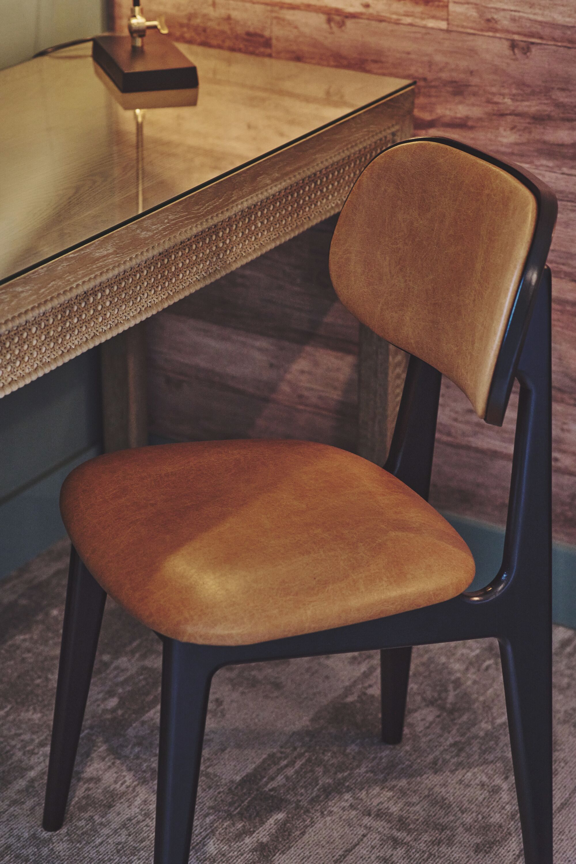 A chair with a cushioned seat and backrest, positioned in front of a wooden table with a metallic base.