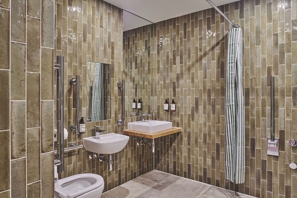 Un baño con inodoro, dos lavamanos, un espejo y cortina de ducha.