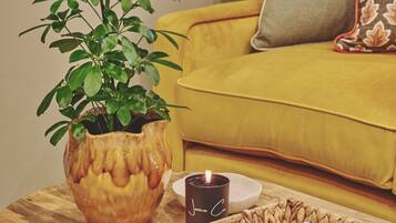 A wooden coffee table with a potted plant, a candle, and a magazine.