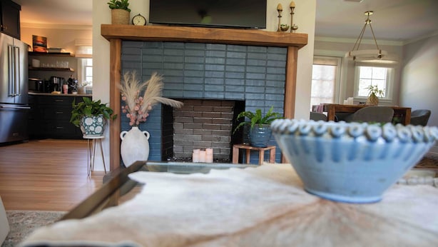 Una sala de estar moderna con chimenea, un comedor y una cocina al fondo.