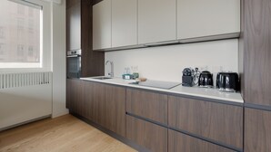 Eine moderne Küche mit Holzausstattung, einem eingebauten Backofen und einem Fenster mit Jalousien.