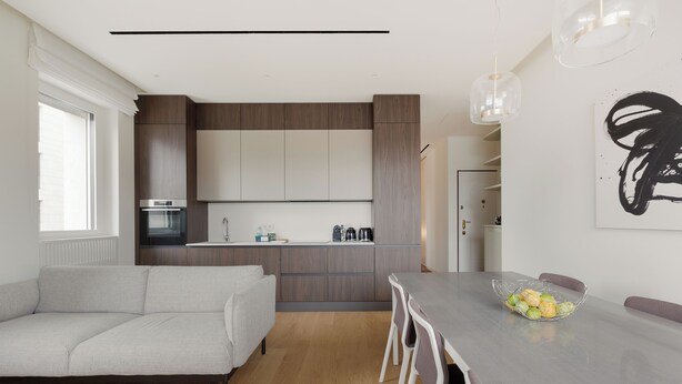 Eine moderne Küche mit Einbauofen, ein Essbereich mit Tisch und Stühlen sowie ein großes Fenster für natürliches Licht.