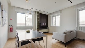Ein modernes Wohnzimmer mit Esstisch, Sofa und integriertem Fernseher.