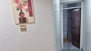Un pasillo con un cuadro de rosas colgado en la pared, una puerta y un suelo con textura.