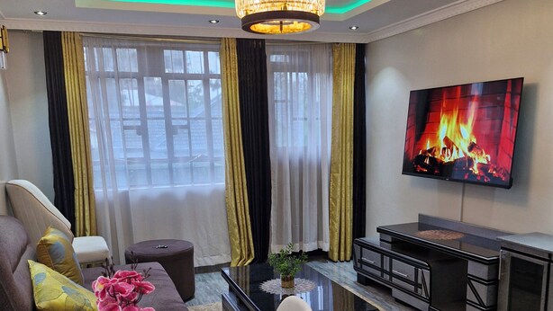 Una sala de estar moderna con una araña, un televisor de pantalla plana, un sofá, una mesa de centro y una chimenea.