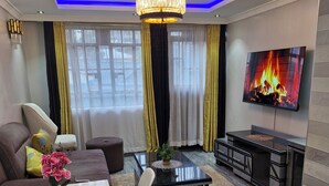 Una sala de estar moderna con una araña, un televisor de pantalla plana, un sofá, una mesa de centro y un mueble para la televisión.
