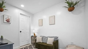 Un couloir avec un canapé vert, un tapis à motifs et une petite table sur laquelle se trouve une lampe.