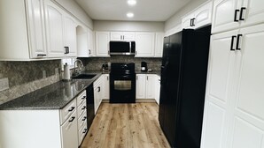 A modern kitchen with white cabinetry, a black refrigerator, and a microwave. - Newly Renovated with heated Pool, close to CWS,
sleeps 12 (Omaha)