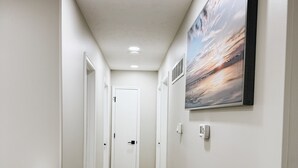 A hallway with wooden flooring, white walls, and a framed picture on the wall. - Newly Renovated with heated Pool, close to CWS,
sleeps 12 (Omaha)