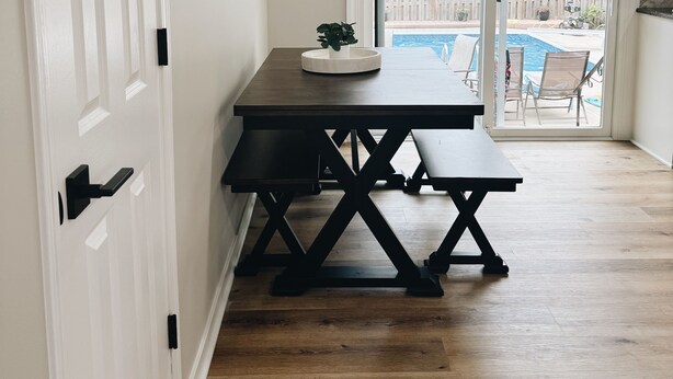 A room with a wooden floor, a dark wooden table with a bench, a sliding glass door leading to a backyard with a pool and patio furniture. - Newly Renovated with heated Pool, close to CWS,
sleeps 12 (Omaha)