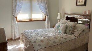 Ein Schlafzimmer mit Bett, Vorhängen am Fenster, Nachttisch und Lampe.