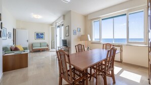 A spacious living area with a wooden dining table and chairs, a sofa, and a television. - The Sound of the Sea by Wonderful Italy (Sanremo)