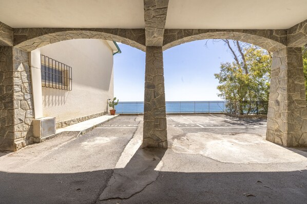 Un espace extérieur abrité, doté de piliers en pierre et offrant une vue sur la mer.