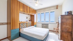A bedroom with a bed, wooden wardrobe, and a window with a view. - The Sound of the Sea by Wonderful Italy (Sanremo)