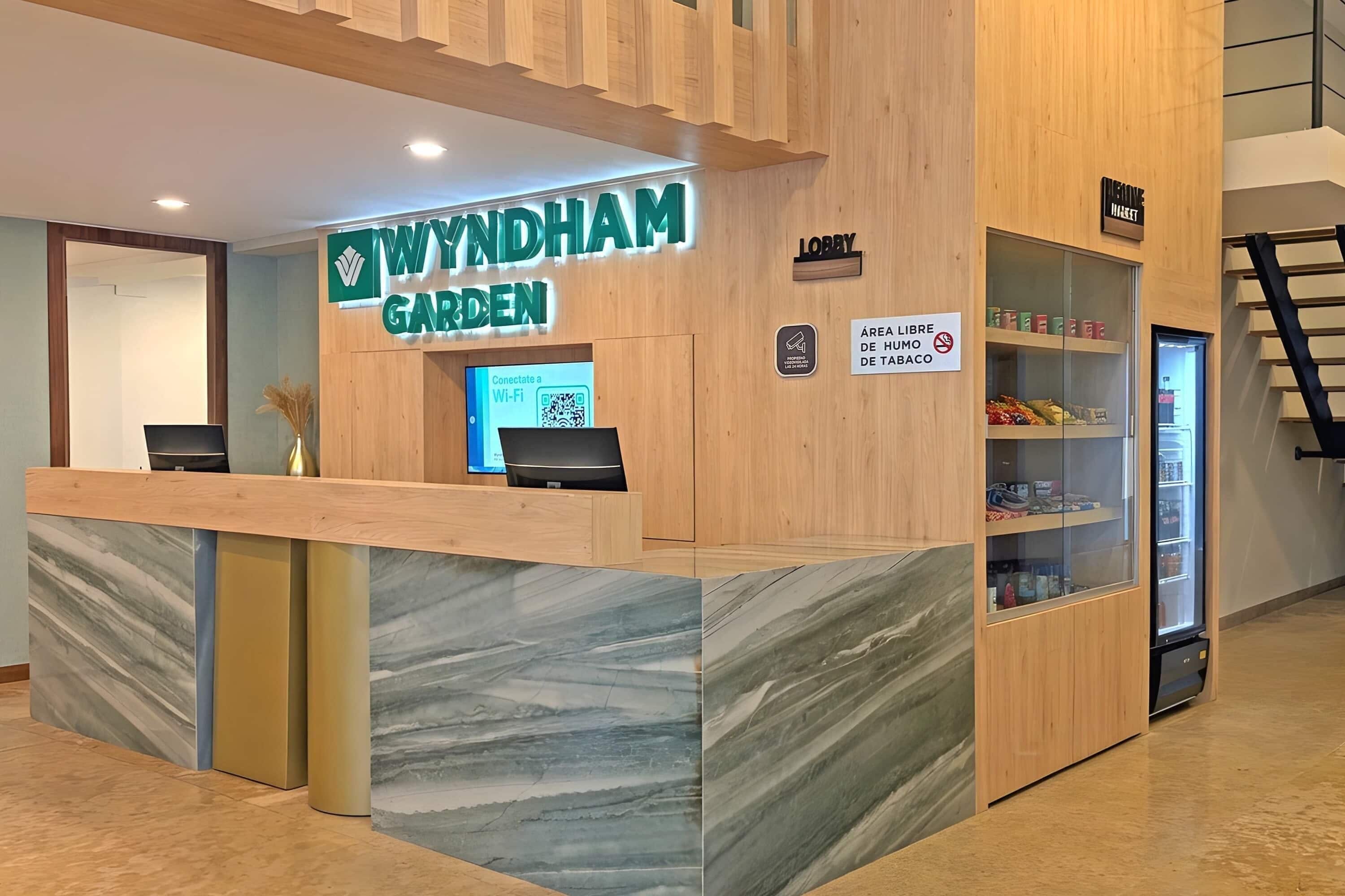 Una recepción con un letrero que dice 'WYNDHAM GARDEN' y un código QR para Wi-Fi.