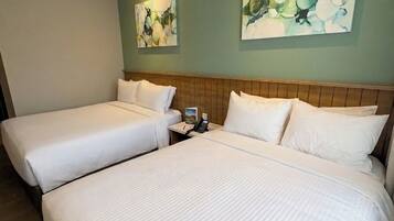 A hotel room with two beds, a nightstand, and two abstract paintings on the wall.