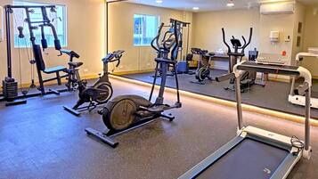 A gym with various exercise equipment including treadmills, stationary bikes, and weight machines.