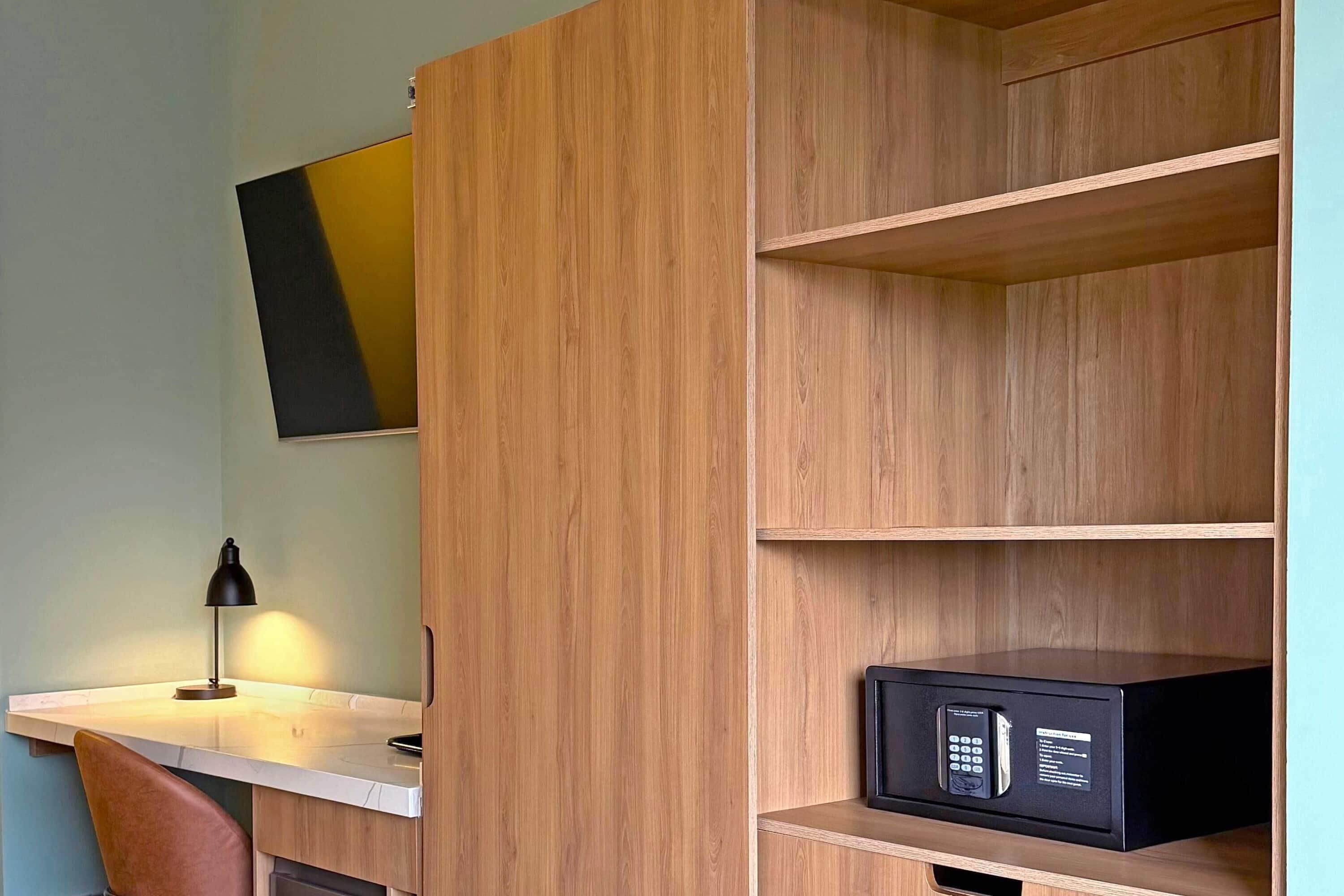 Une chambre moderne avec un bureau en bois, une lampe noire et un coffre-fort.