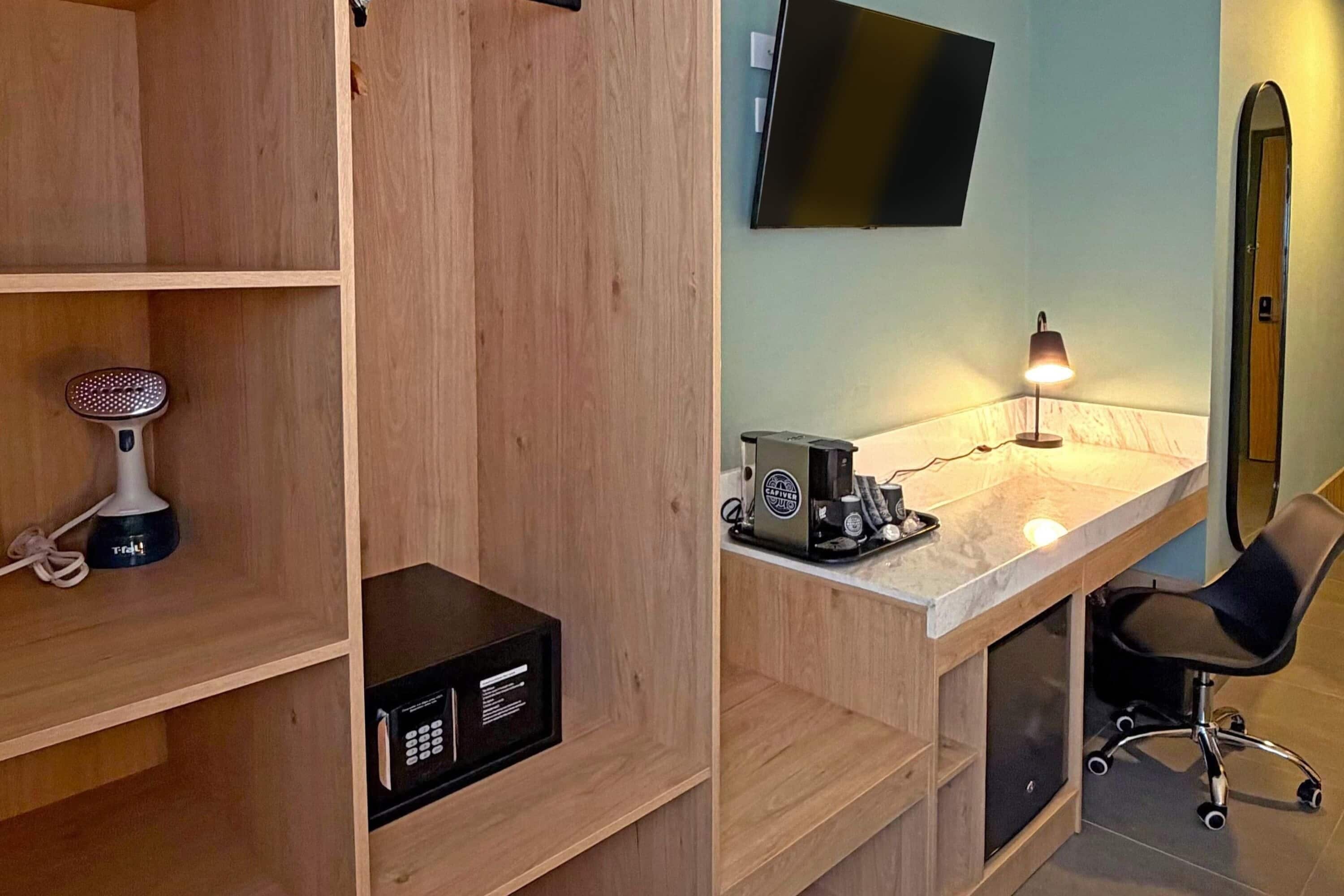A modern room with a wooden desk, a chair, a flat-screen TV mounted on the wall, and a coffee machine on the desk.
