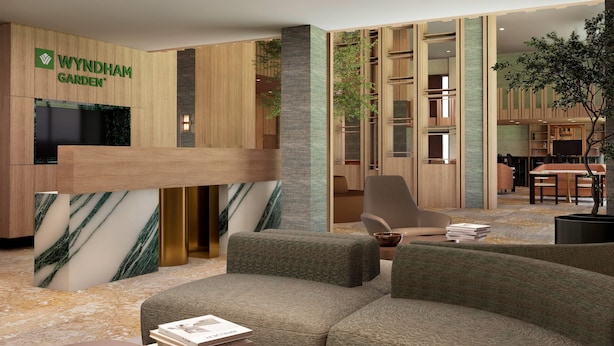A modern reception area with a wooden reception desk, a seating area with sofas, and a visible plant.