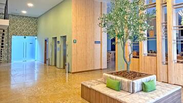 A hotel lobby with a reception desk, a plant, and a seating area.