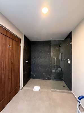 A room with a wooden door, a glass shower enclosure, and a white ceiling light.
