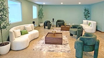 A spacious living room with a sofa, armchairs, a coffee table, and potted plants.