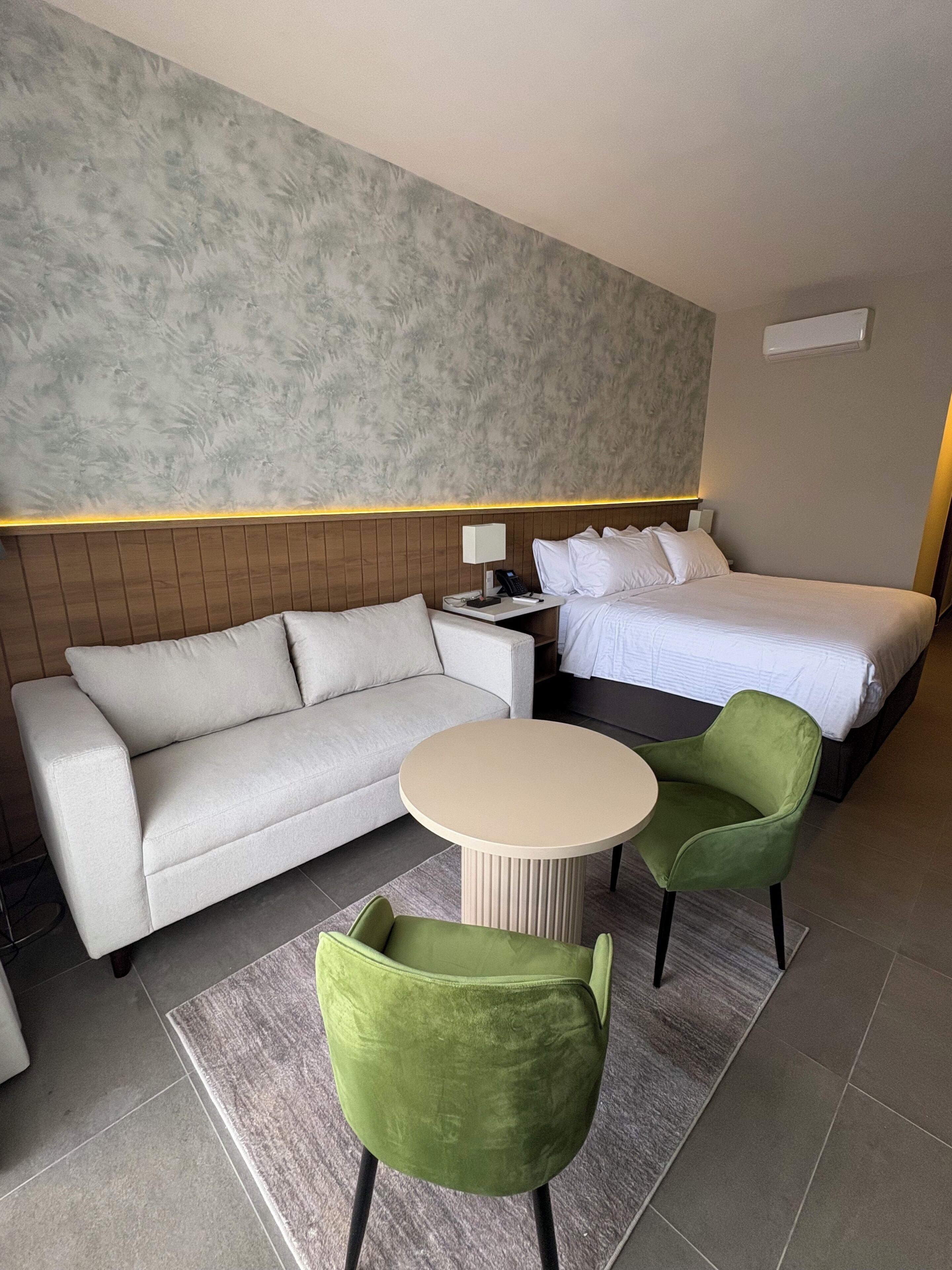 A hotel room with a bed, a sofa, a small table, and two chairs.
