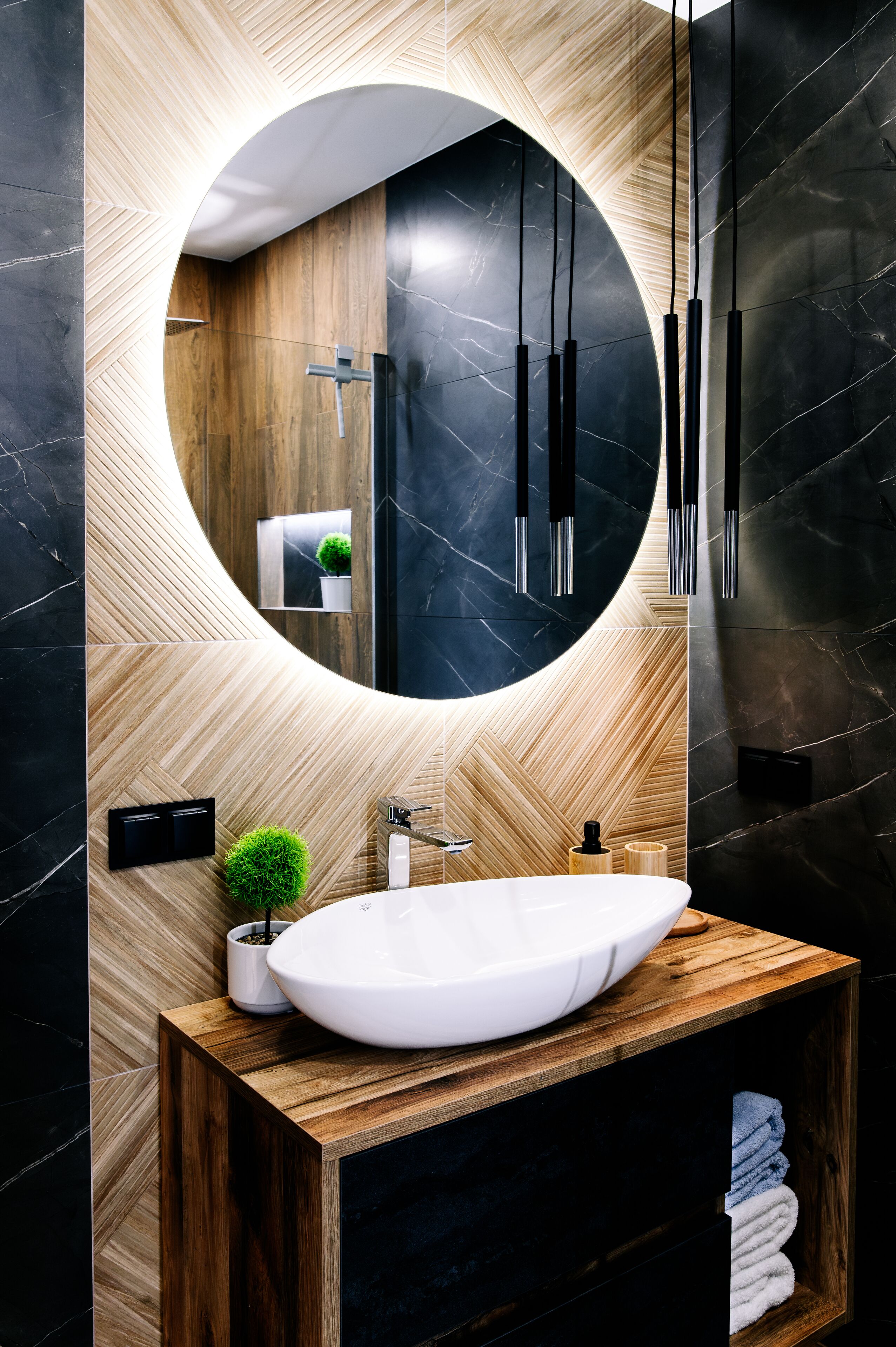 Ein modernes Badezimmer mit einem Holzwaschtisch, einem runden Spiegel und einem weißen Waschbecken.