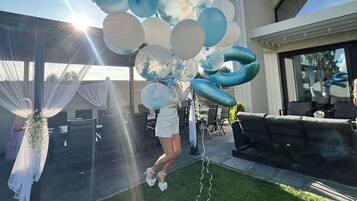 A person holding a cluster of balloons outdoors with a building in the background.