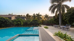 A swimming pool with lounge chairs and a patio area with tables and chairs.