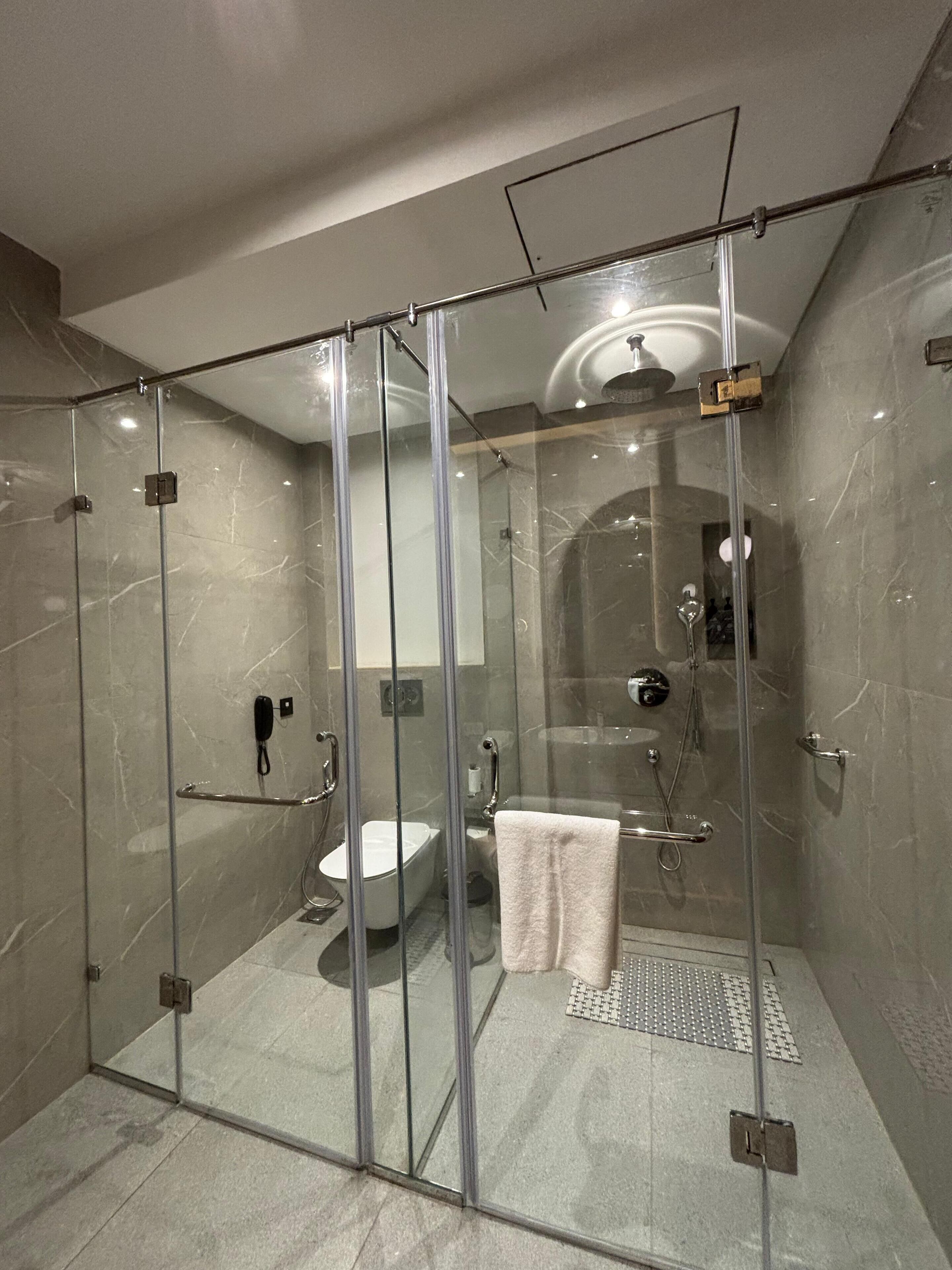 Un área de ducha moderna con mampara de vidrio, una bañera blanca y un box de ducha con paredes de vidrio.
