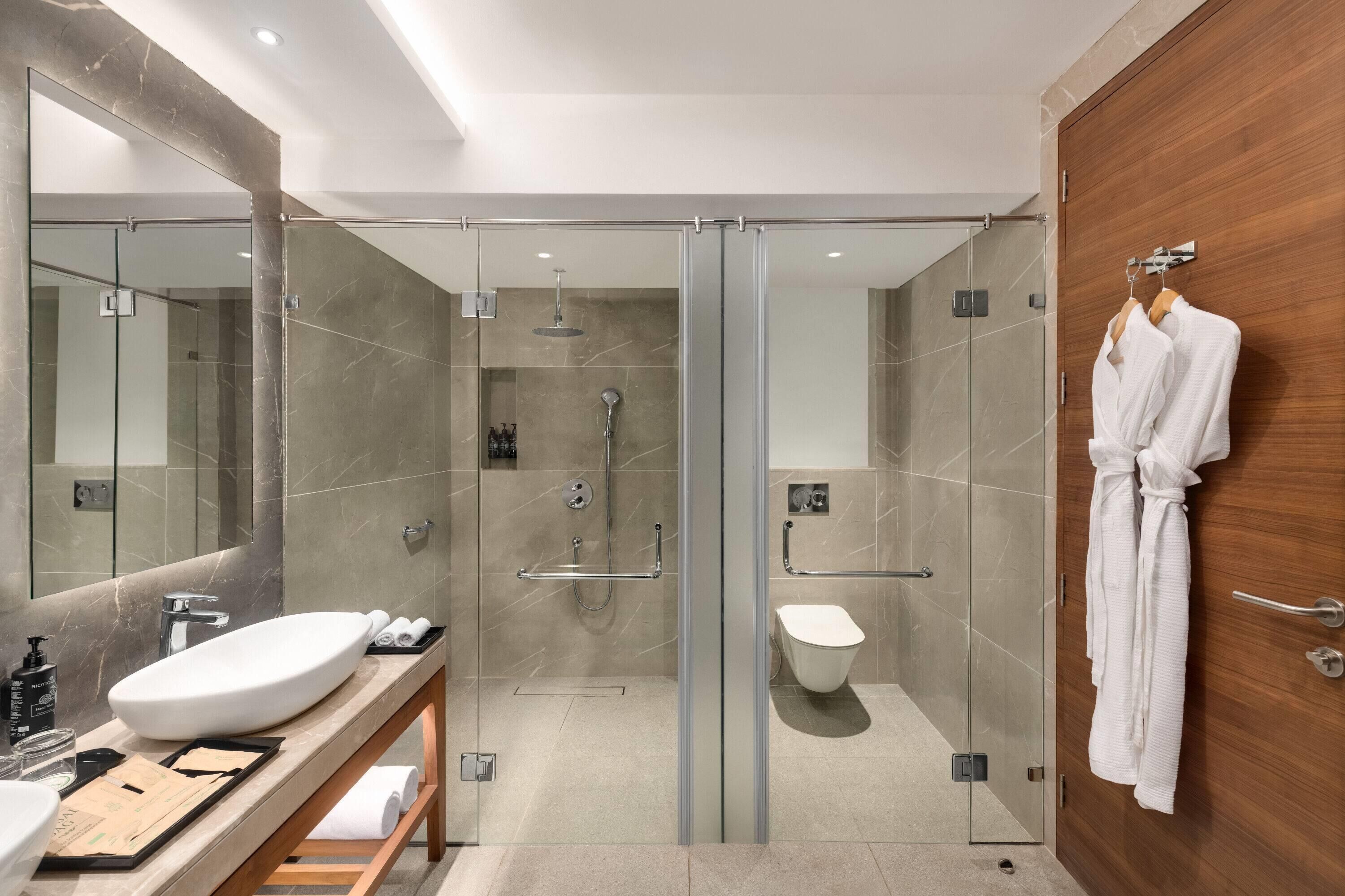 A modern bathroom with a glass-enclosed shower, a white sink, and a wooden vanity.