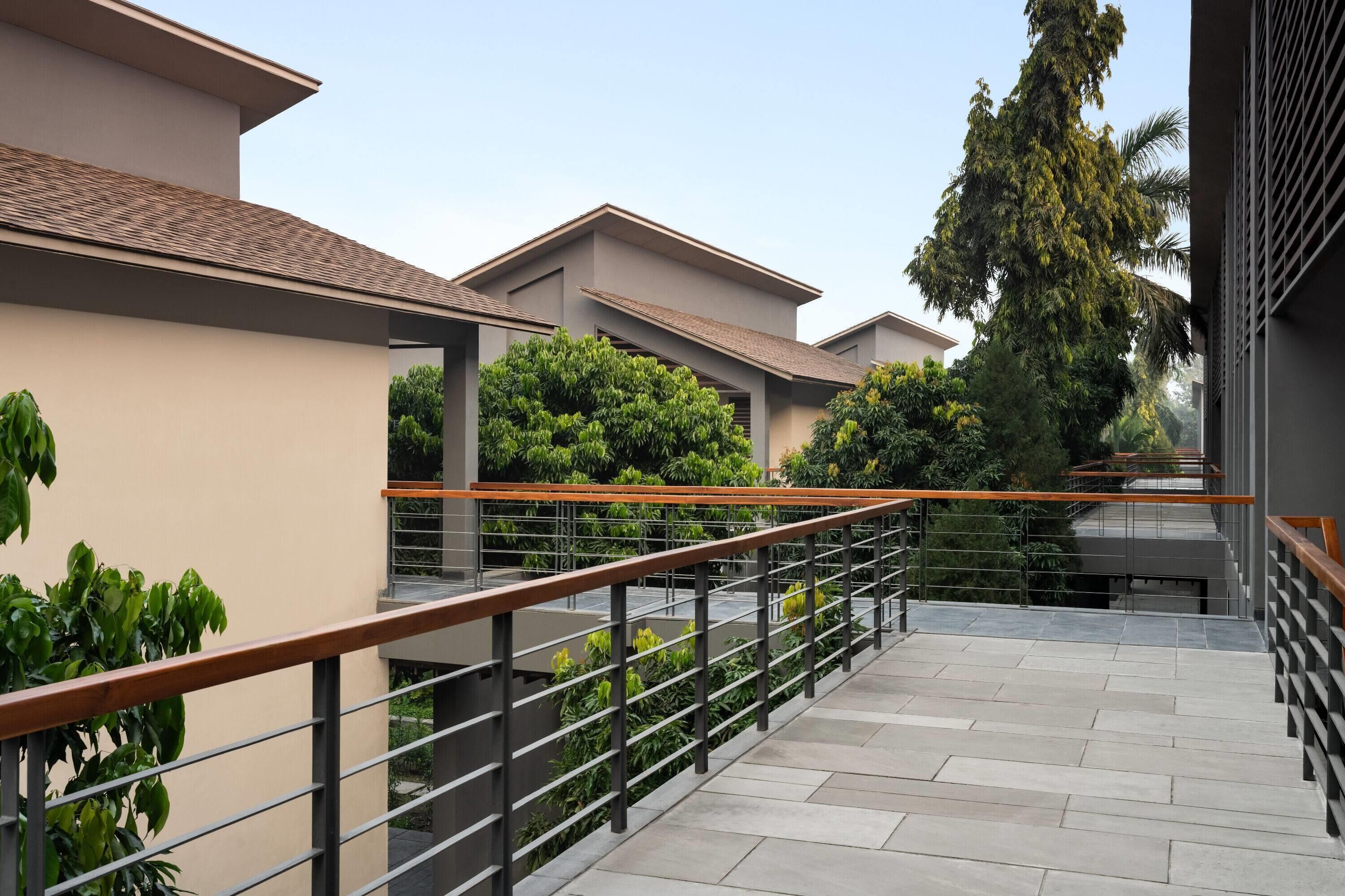 A modern building with a flat roof, a balcony with metal railings, and a staircase leading to an upper level.
