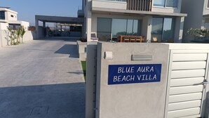 A modern villa with a sign reading "BLUE AVRA BEACH VILLA".