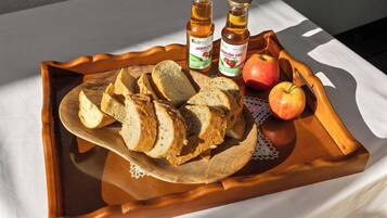 Ein Holztablett mit Scheibenbrot, einem ganzen Apfel und zwei Flaschen Jablonec-Sirup.