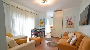 A living room with a sofa, ottoman, and a dining area with chairs and a table. - Seaside retreat with stunning sea views – steps from the beach, pure relaxation. (Vlore)