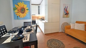 A modern living room with a dining area, featuring a sofa, a table set for four, and artwork on the walls. - Seaside retreat with stunning sea views – steps from the beach, pure relaxation. (Vlore)