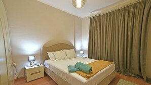 A neatly made bed with pillows and a blanket, a bedside lamp, and a nightstand. - Seaside retreat with stunning sea views – steps from the beach, pure relaxation. (Vlore)