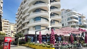 A multi-story hotel with balconies, outdoor seating, and a red ATM. - Seaside retreat with stunning sea views – steps from the beach, pure relaxation. (Vlore)